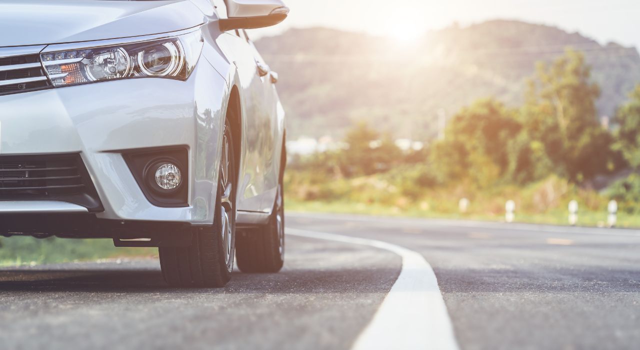 Weißes Auto auf Landstraße in Kurve mit optimaler Achsgeometrie
